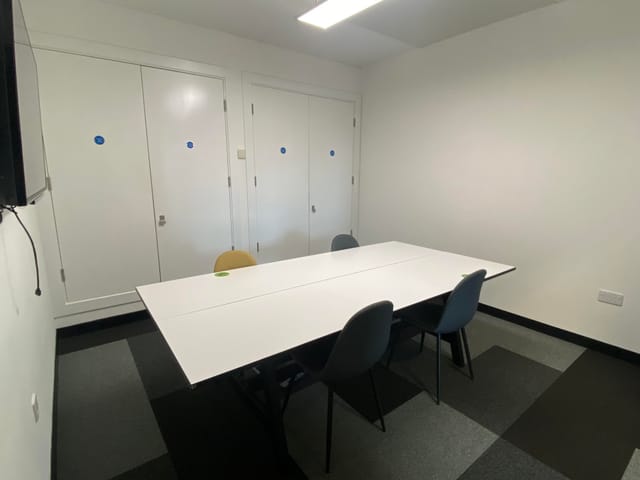 Minimalist meeting room with large white table, ideal for team meetings and presentations.