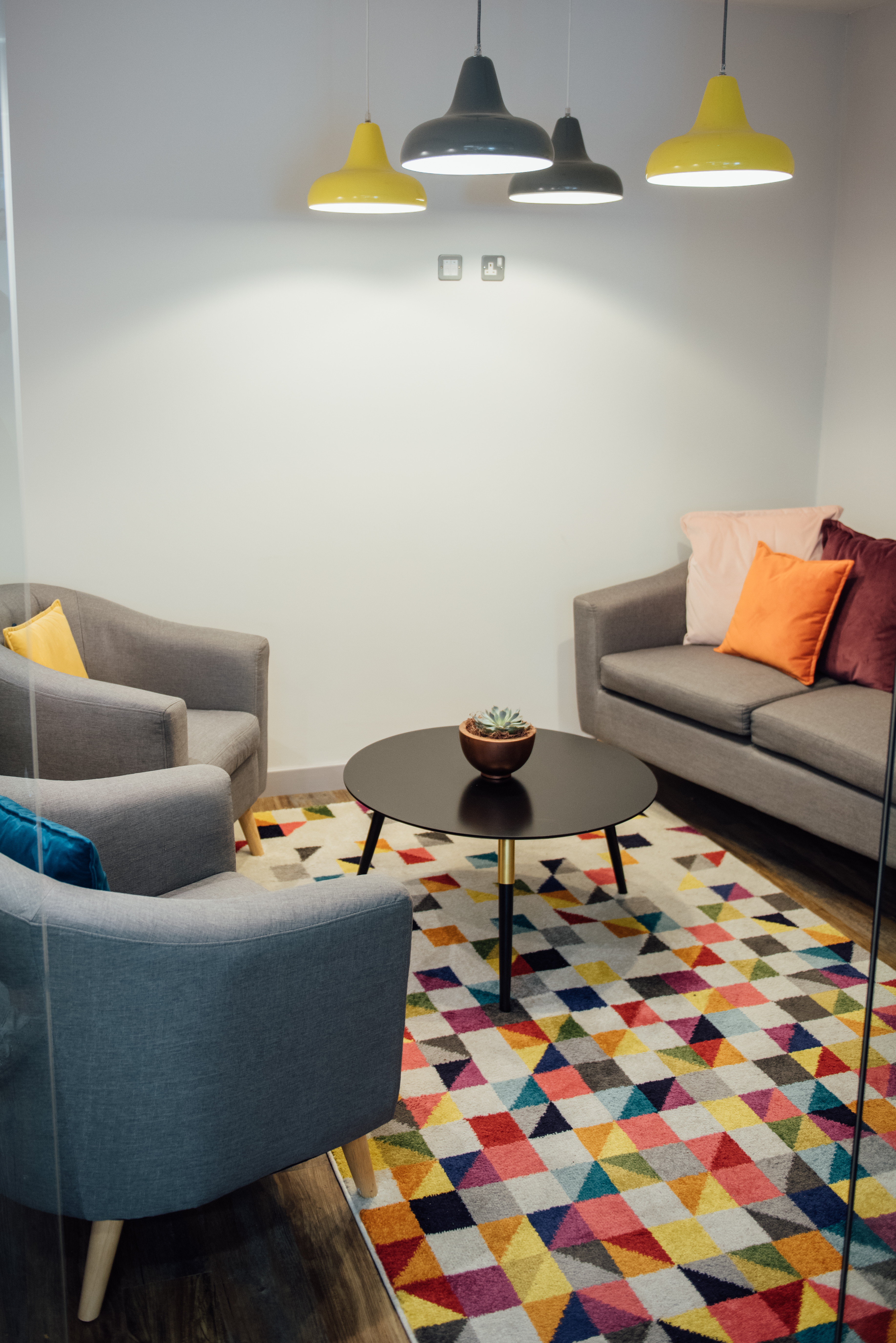 Cozy meeting space in Wizu Workspace with vibrant rug for informal brainstorming sessions.