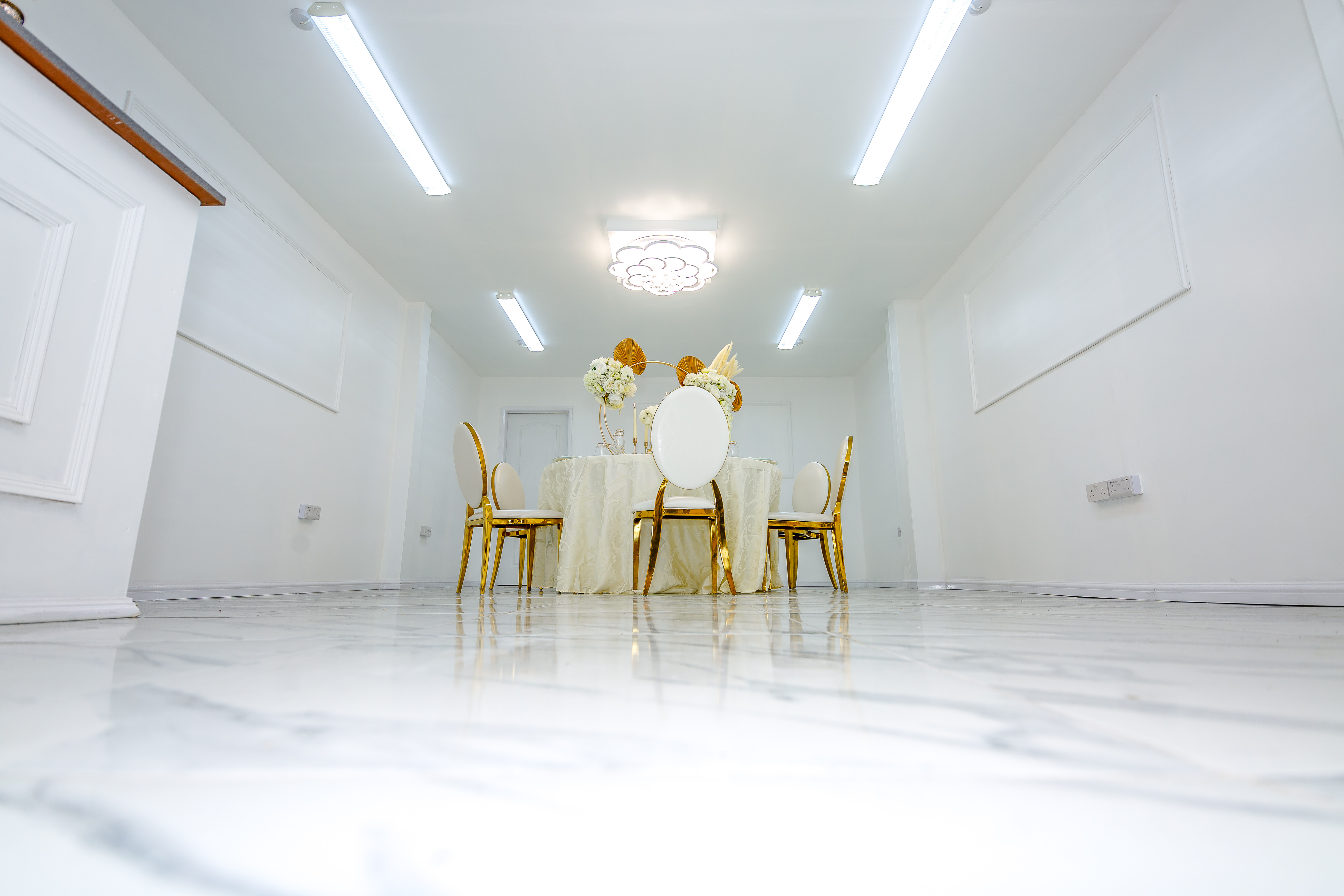 Modern event space at G LUXE Place with elegant floral arrangements and gold-accented chairs.