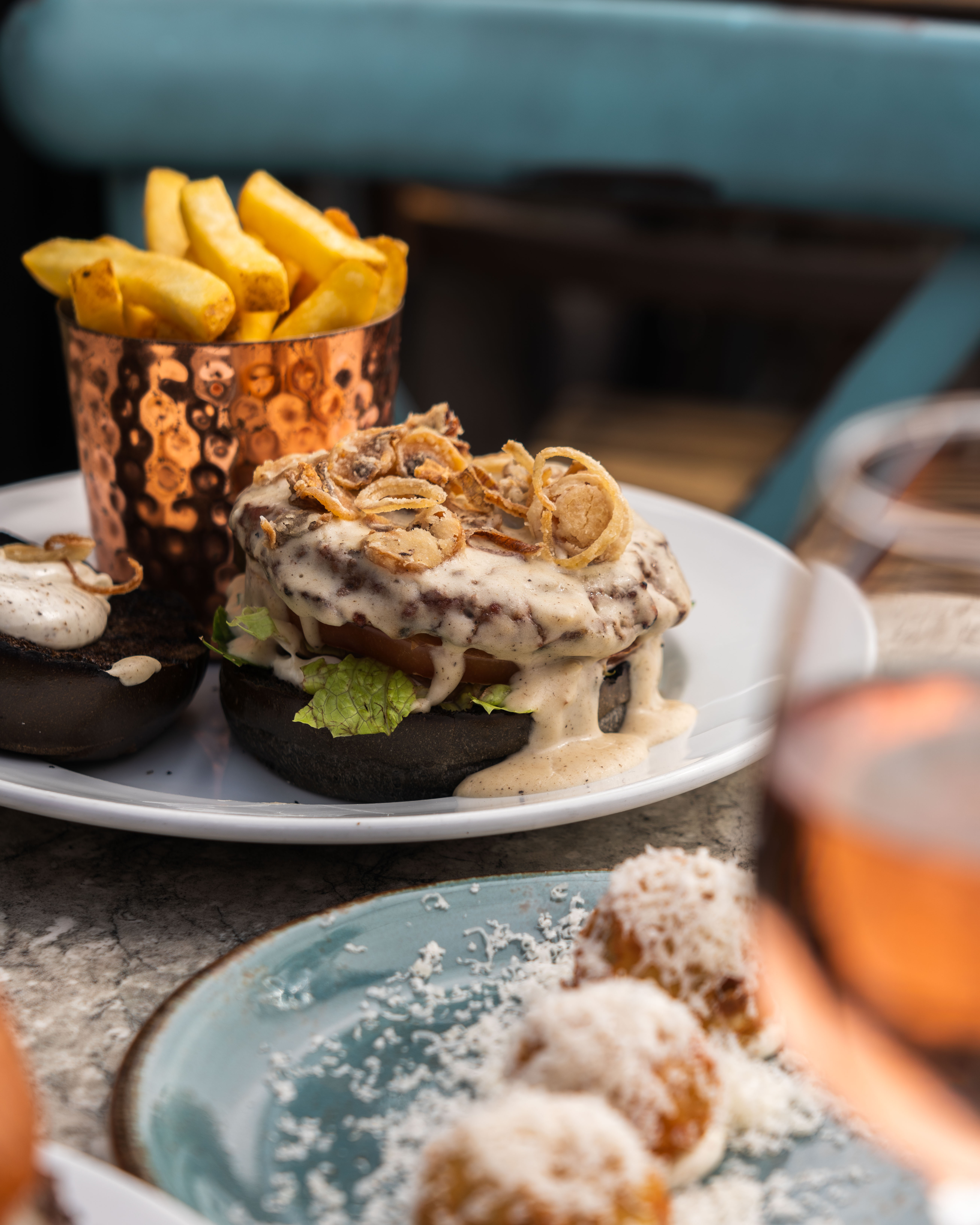 Gourmet burger with crispy onions and fries at Terrace, Paradiso London event catering. - Banner