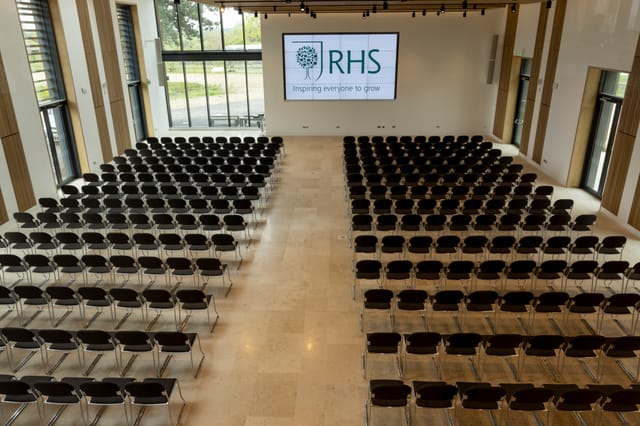 Hilltop Garden Room at RHS Wisley, spacious venue for conferences with black chairs.