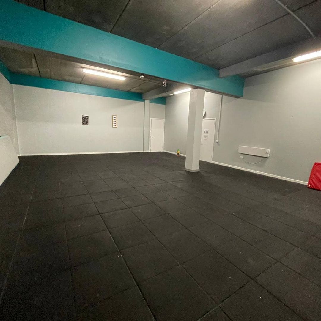 Spacious dance studio with rubber flooring for workshops and fitness classes.