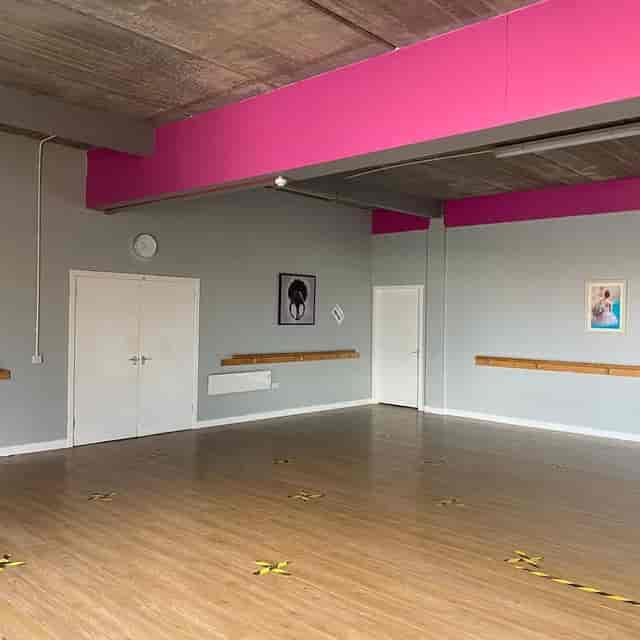 Dance studio with wooden flooring and pink accents, ideal for workshops and dance classes.