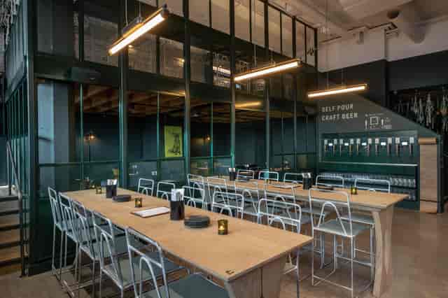 Modern industrial event space with communal table and craft beer taps for networking.