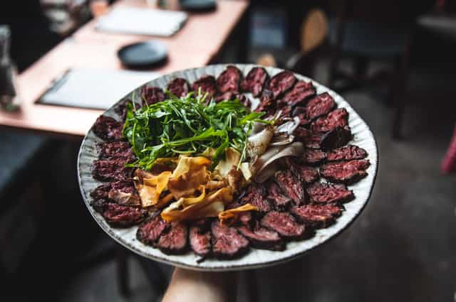 Sliced meat platter with greens and veggies at VAGABOND MONUMENT event catering.