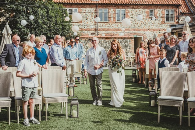 Outdoor wedding ceremony in The Garden Room, featuring a bride and elegant decor.