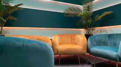 Stylish podcast studio lounge with teal and gold decor for networking events.