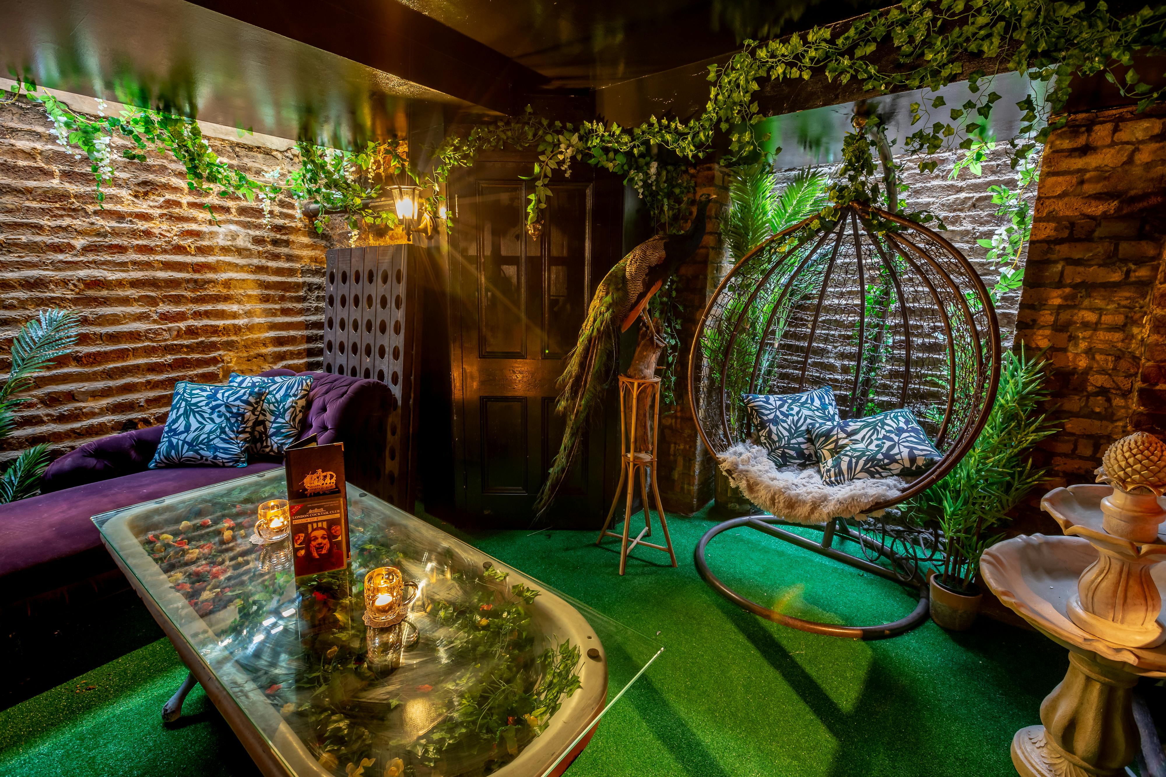 Cozy London Cocktail Club with greenery, brick walls, and unique hanging chair for events.