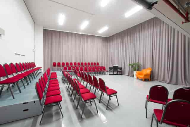 Versatile event space with red chairs at Old Diorama Arts Centre for presentations and workshops.
