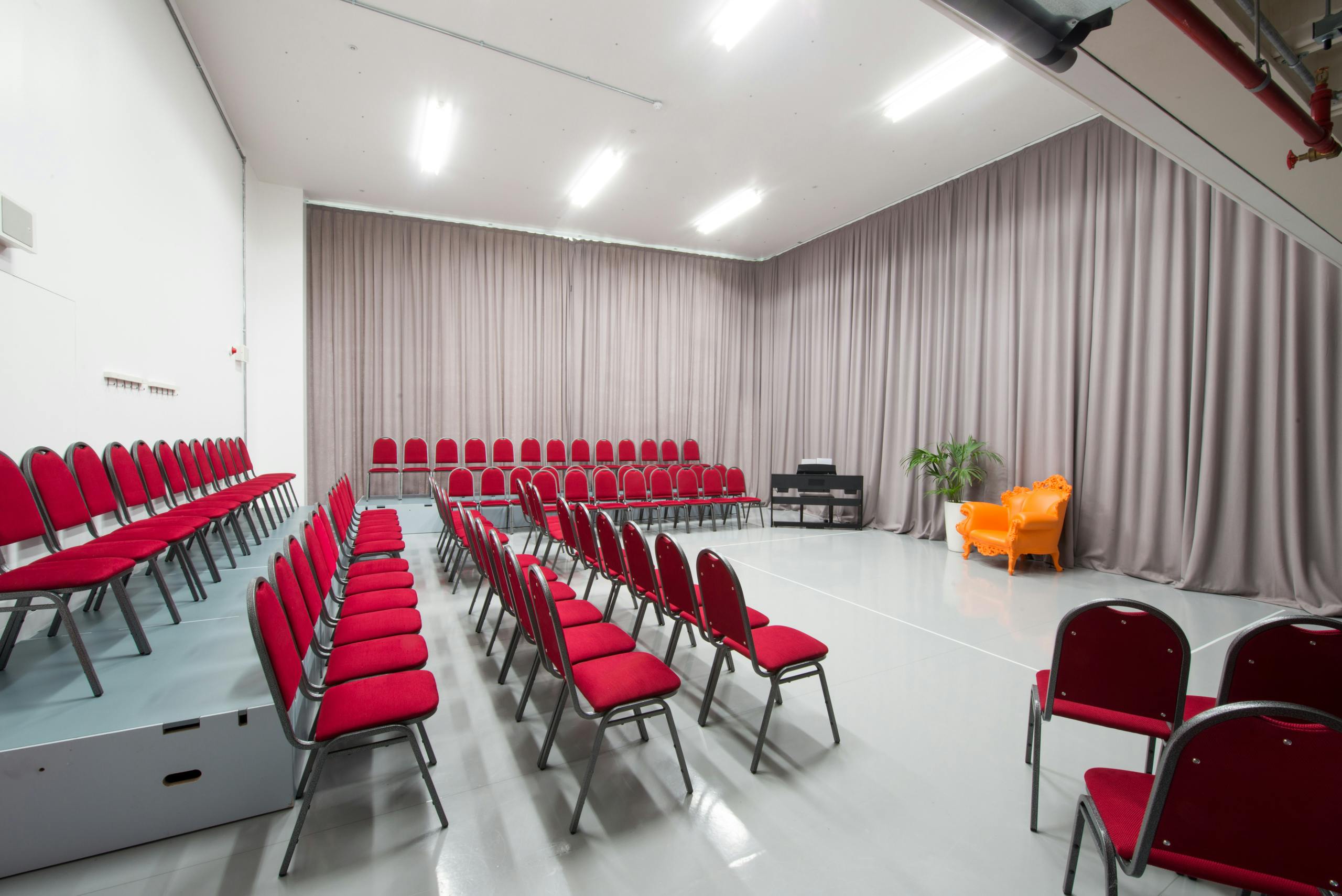 Versatile event space with red chairs at Old Diorama Arts Centre for presentations and workshops.
