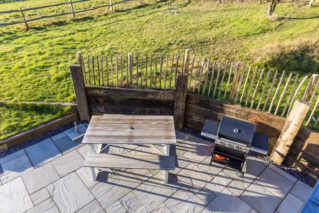 Outdoor event space at The Grain Store Lewes with rustic picnic table and grill.