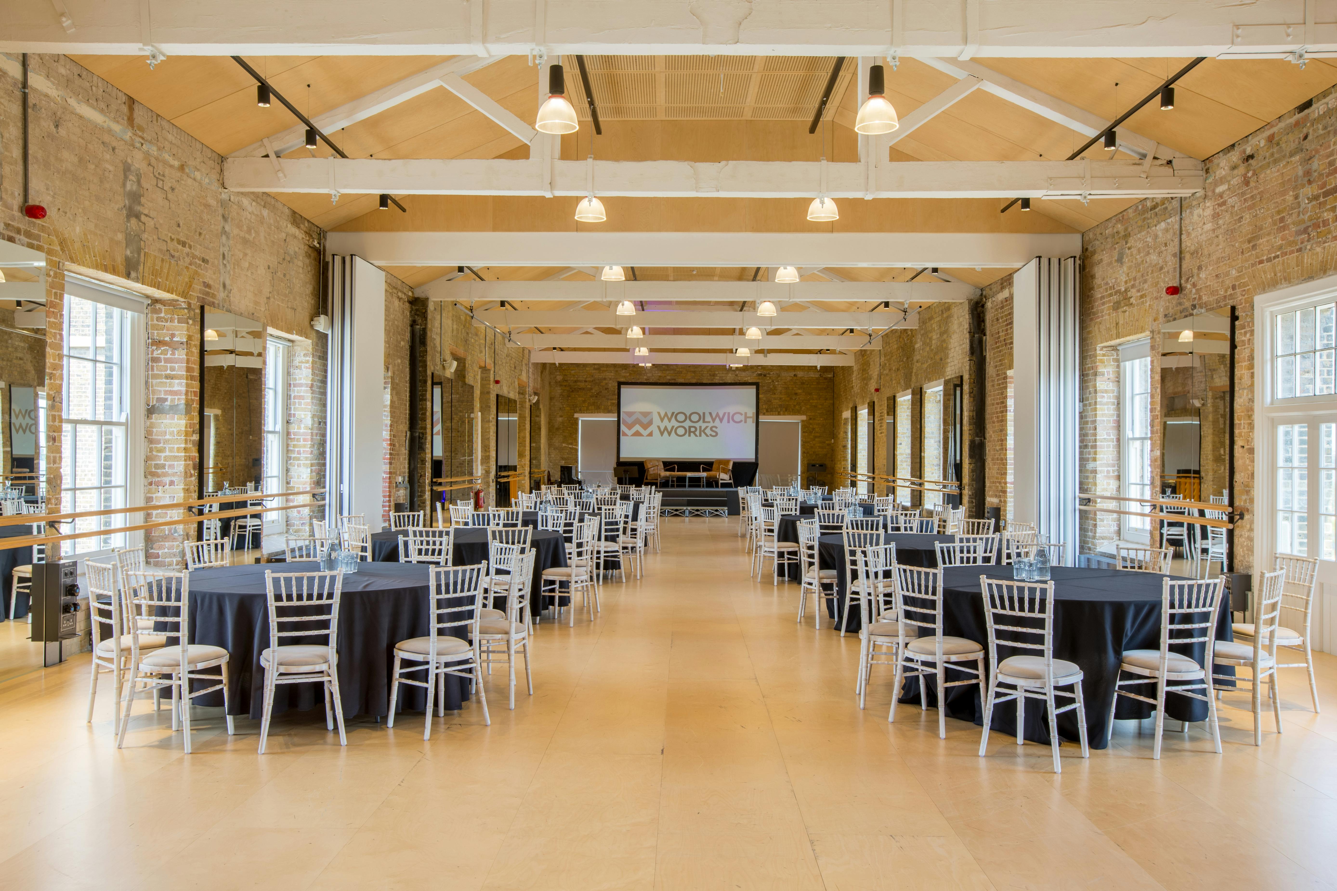 Spacious event venue with round tables, ideal for meetings and banquets in Woolwich Works.