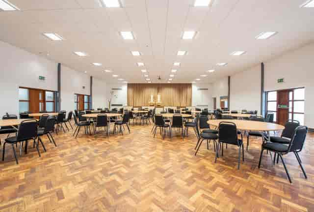 Spacious St Georges Community Hub Hall set for meetings and banquets with round tables.