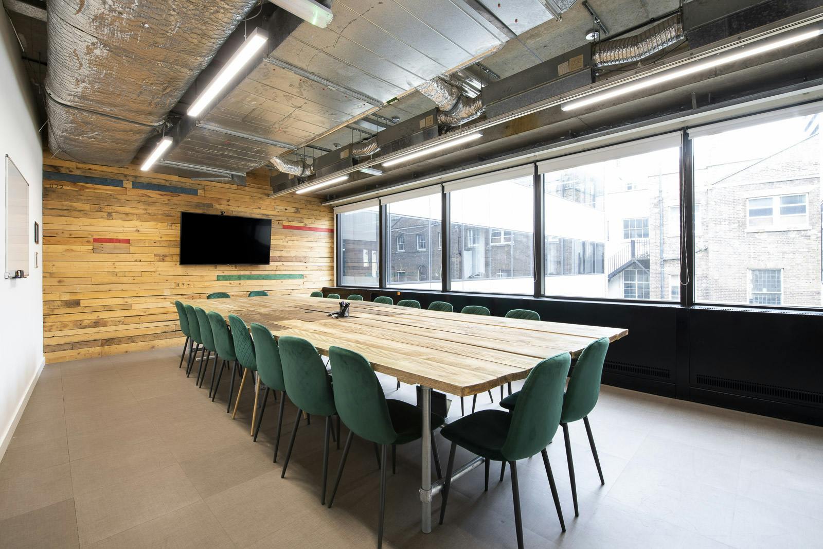 Modern meeting room with wooden table and green chairs at Runway East Borough Market.