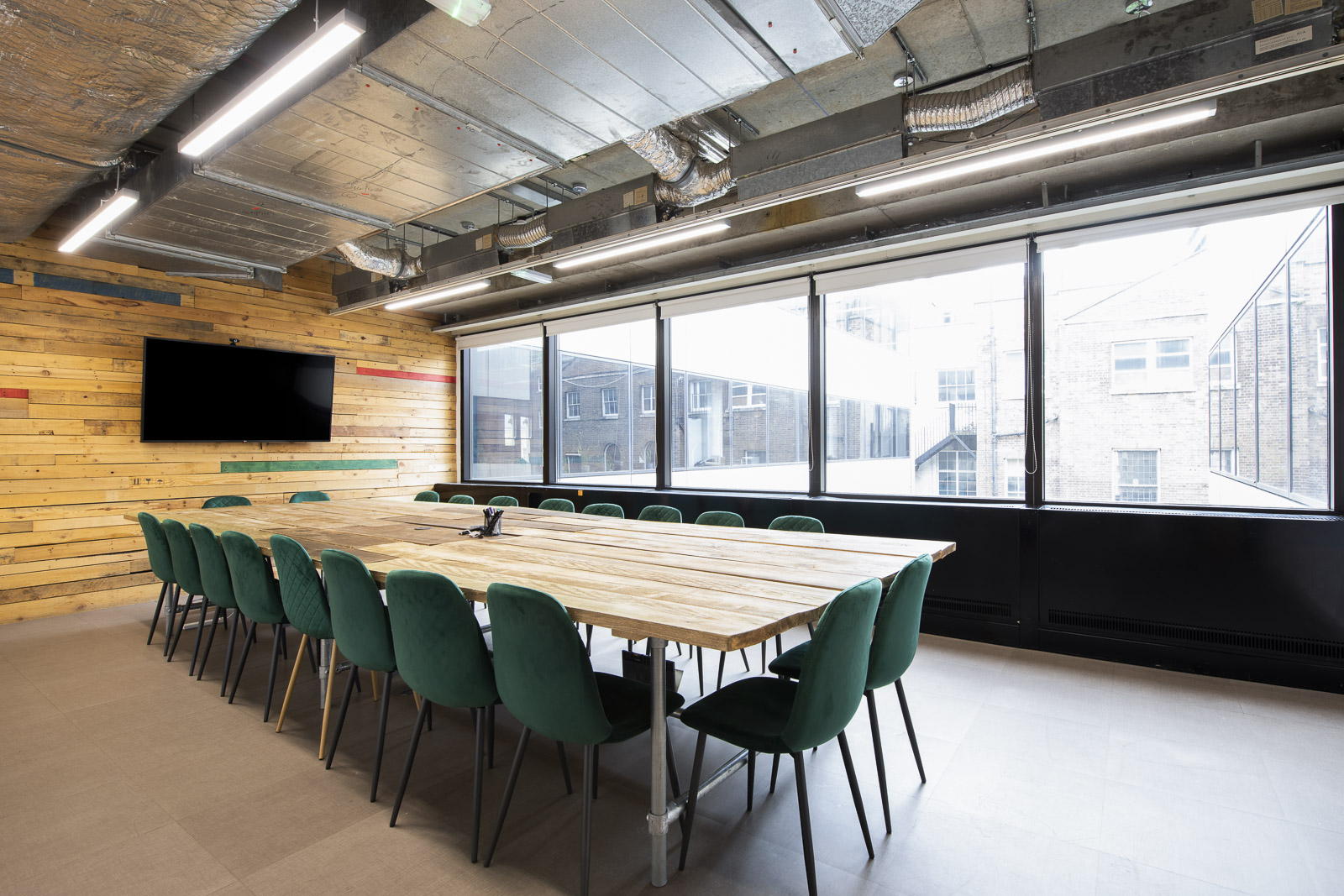 Modern meeting room with wooden table and green chairs at Runway East Borough Market. - Banner