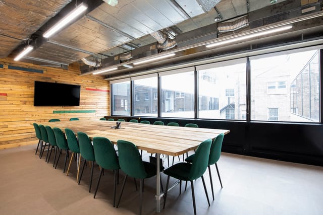 Modern meeting room with wooden table and green chairs at Runway East Borough Market.