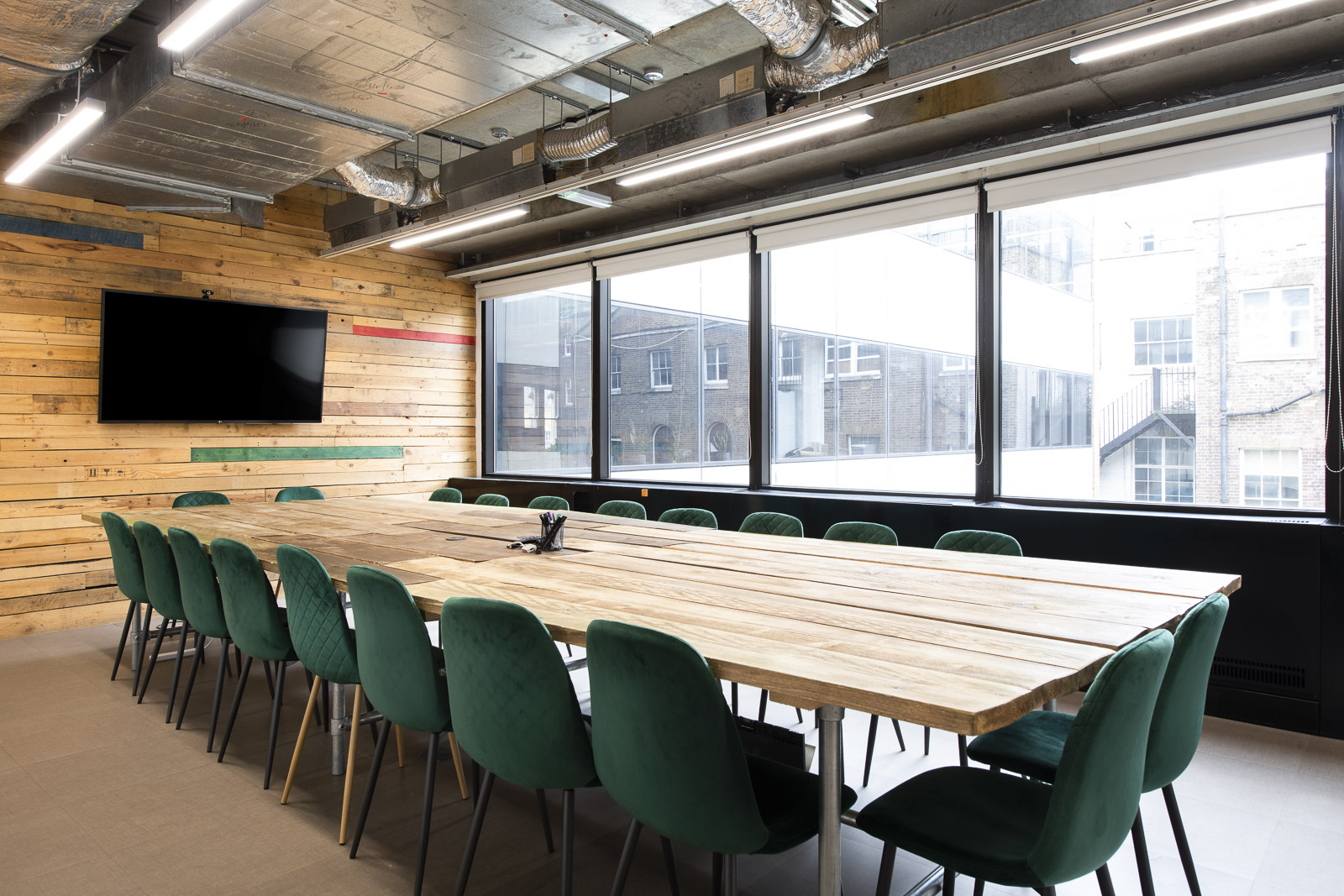 Modern conference room with wooden table and green chairs at Runway East Borough Market. - Banner