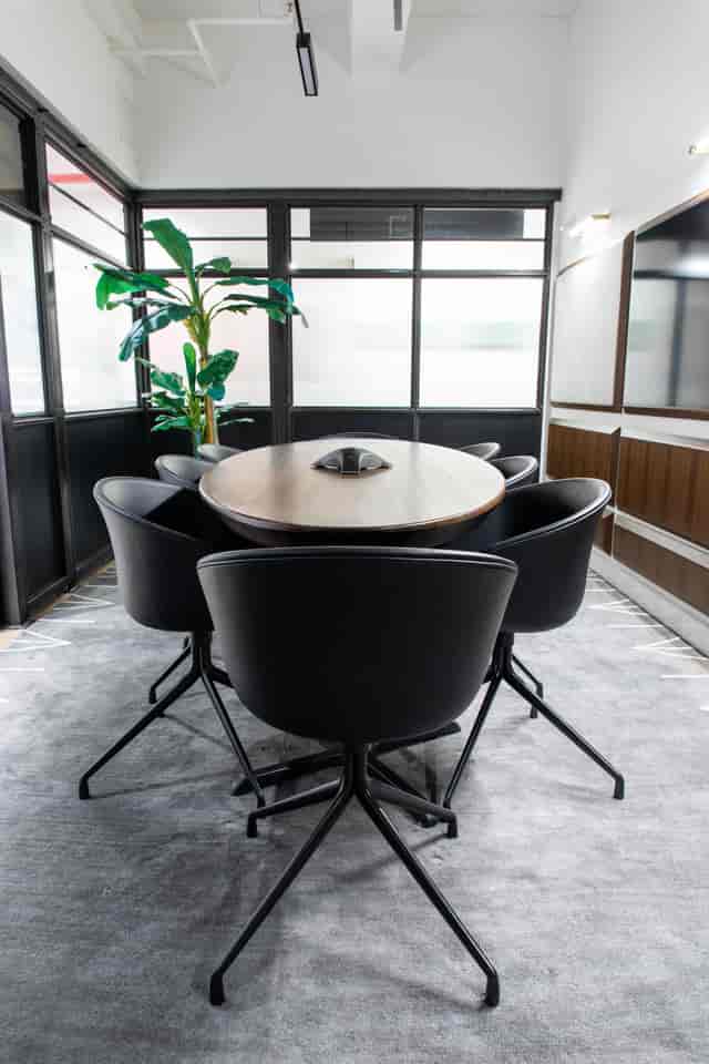 Modern conference room with round wooden table and sleek black chairs, ideal for meetings.