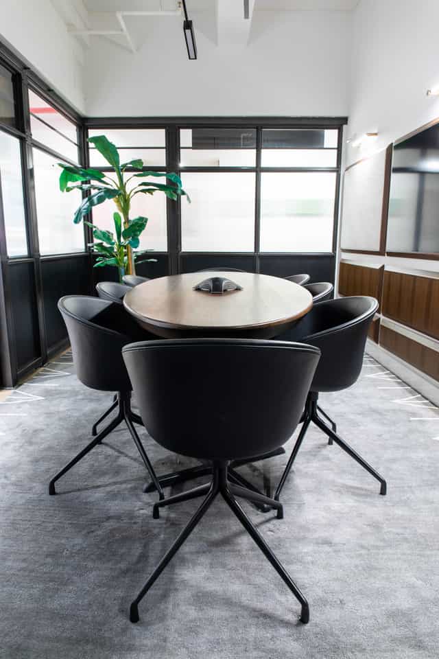 Modern conference room with round wooden table and sleek black chairs, ideal for meetings.