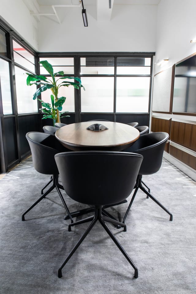 Modern conference room with round wooden table and sleek black chairs, ideal for meetings.