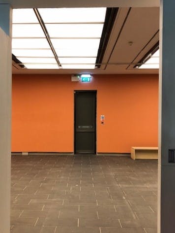 Minimalist event space with orange accent wall, ideal for gatherings and meetings.