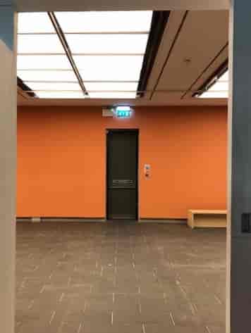 Minimalist event space with orange accent wall, ideal for gatherings and meetings.