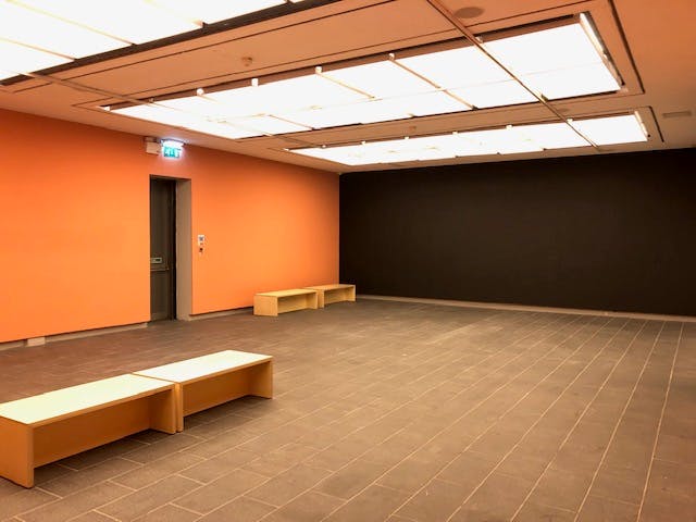 Modern event space with orange accent wall, ideal for workshops and gatherings.