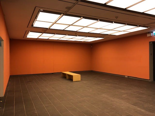 Versatile event space with vibrant orange walls for workshops and presentations.