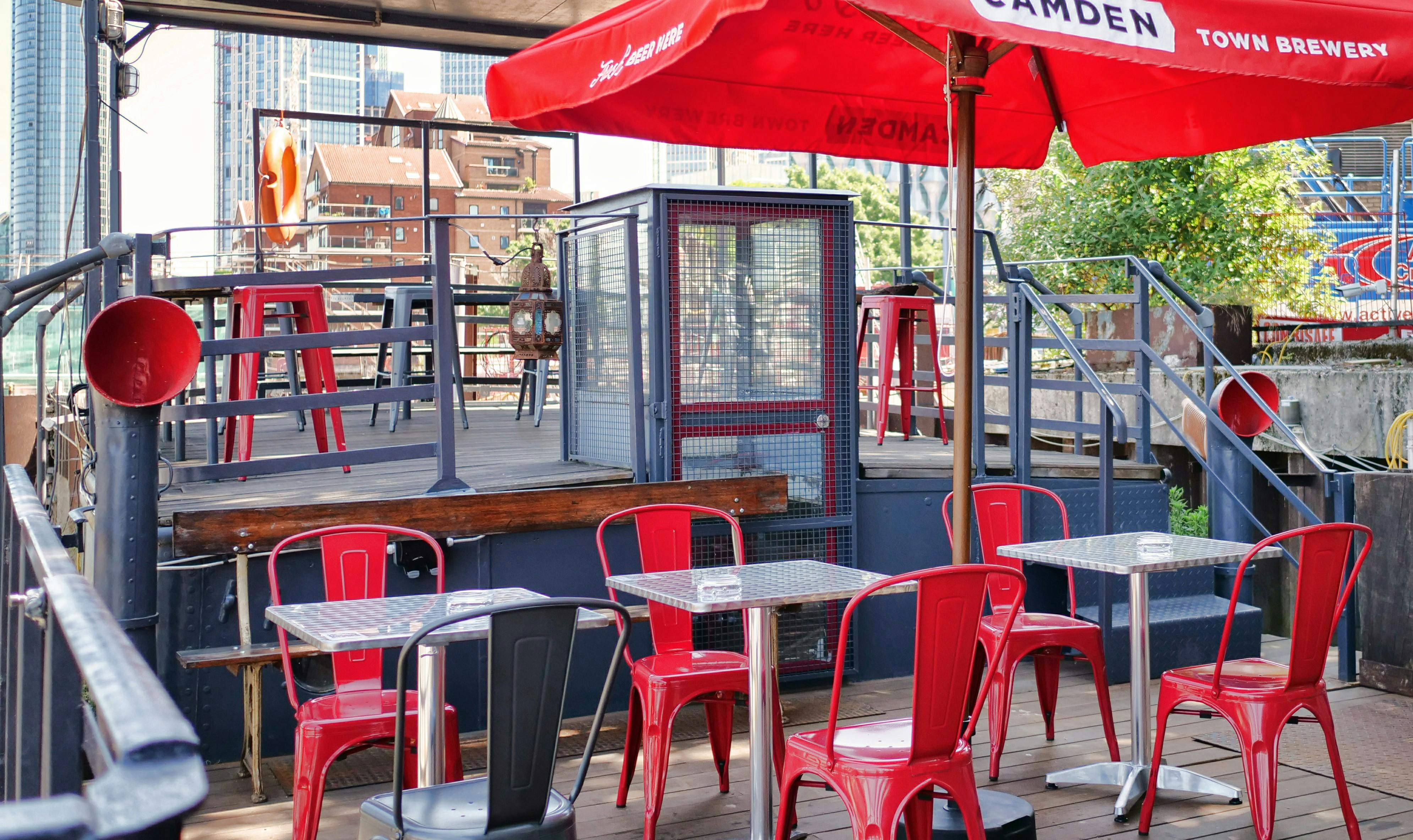 Outdoor East Deck at Battersea Barge with red chairs, ideal for summer networking events.