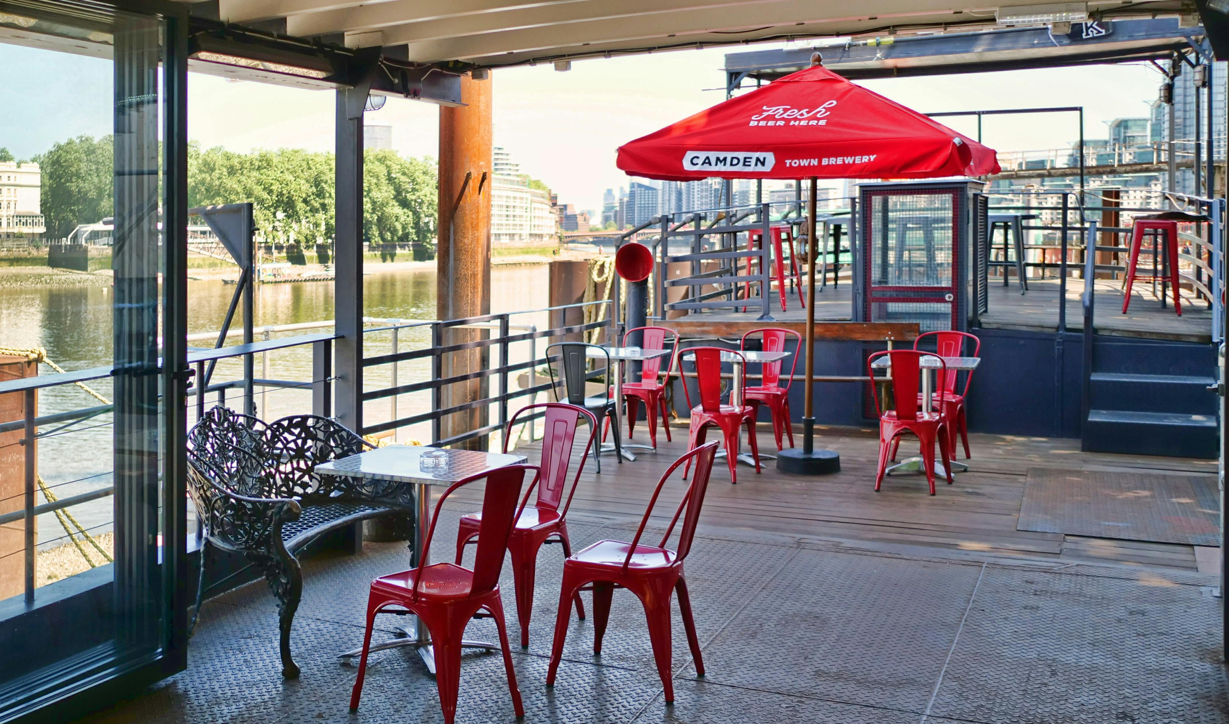 Vibrant outdoor event space with red chairs at Battersea Barge, perfect for gatherings.