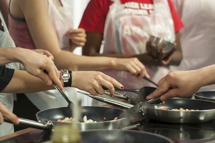 Team-building cooking class at Jenius Social with participants in aprons.