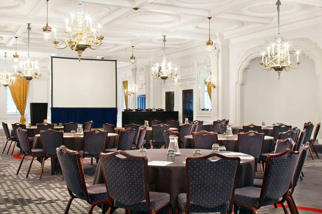 Sophisticated event space with round tables and chandeliers for corporate meetings.