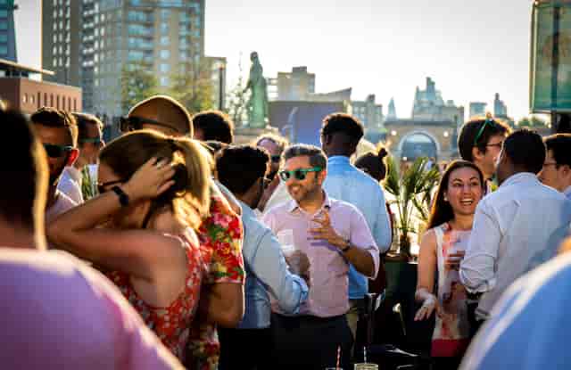 Rooftop event at London Museum Docklands with stylish guests and city skyline.