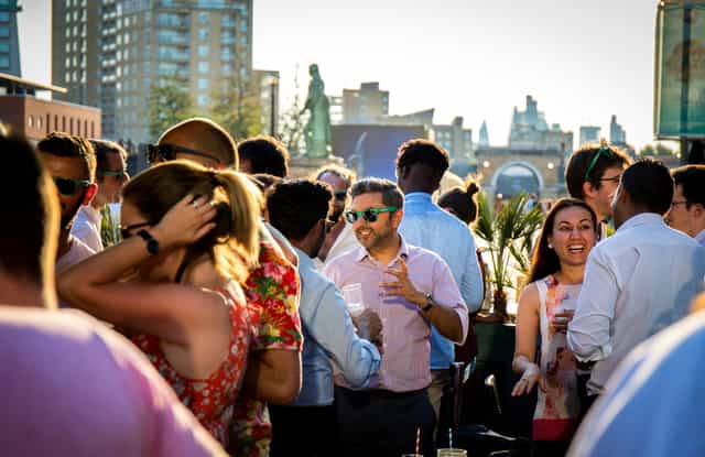 Rooftop event at London Museum Docklands with stylish guests and city skyline.