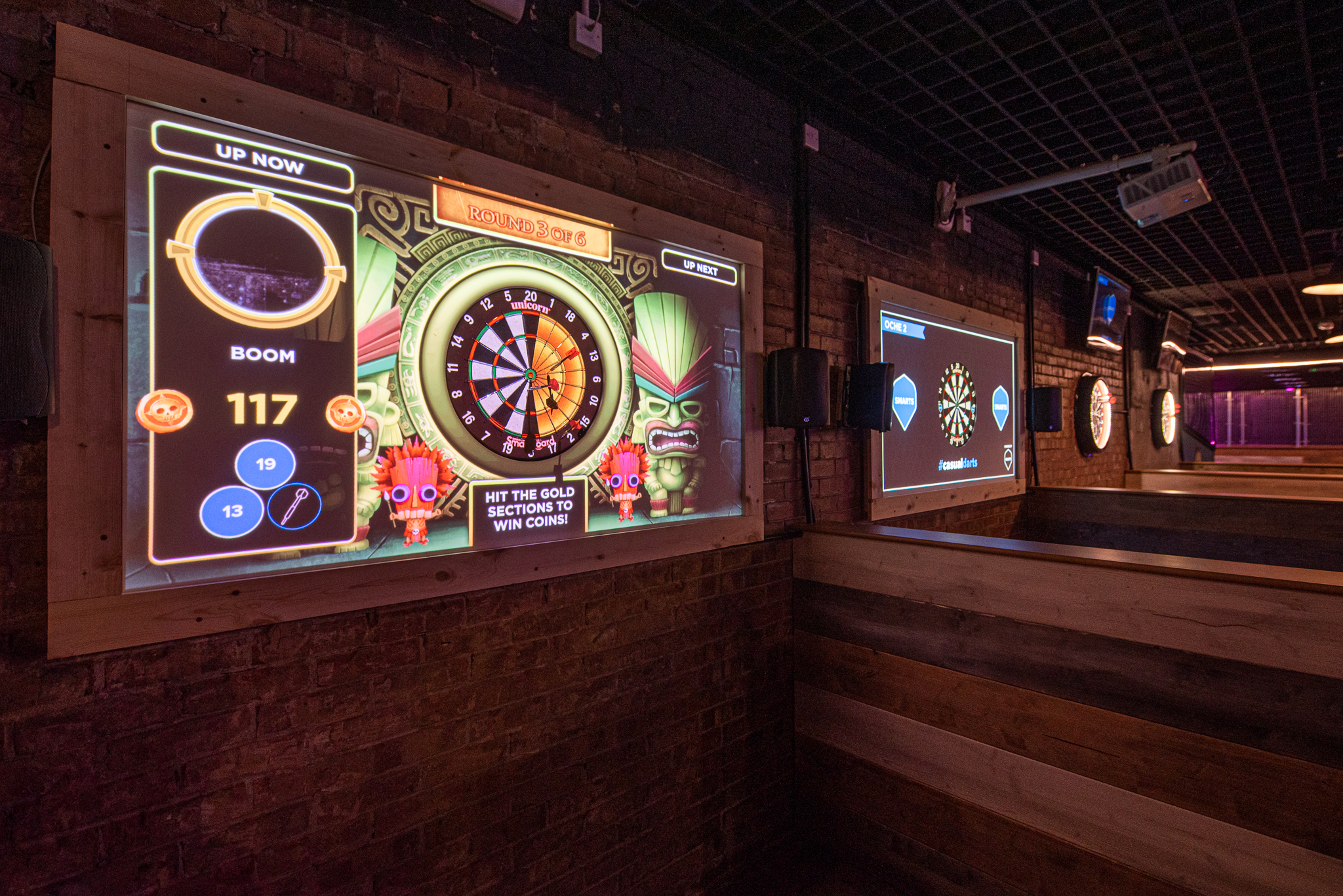 "Interactive event space with digital dartboards at Boom Battle Bar for team-building activities." - Banner