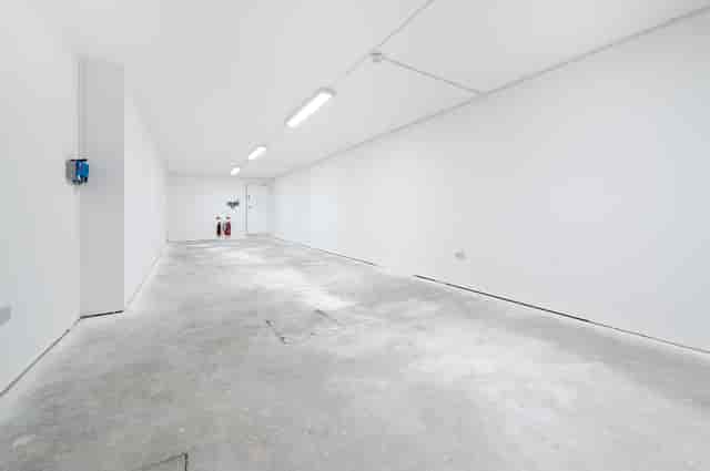 Minimalist event space with white walls and concrete floor, perfect for creative setups.