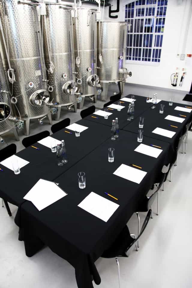 Tank Room at London Cru Winery: industrial meeting space with black table for corporate retreats.