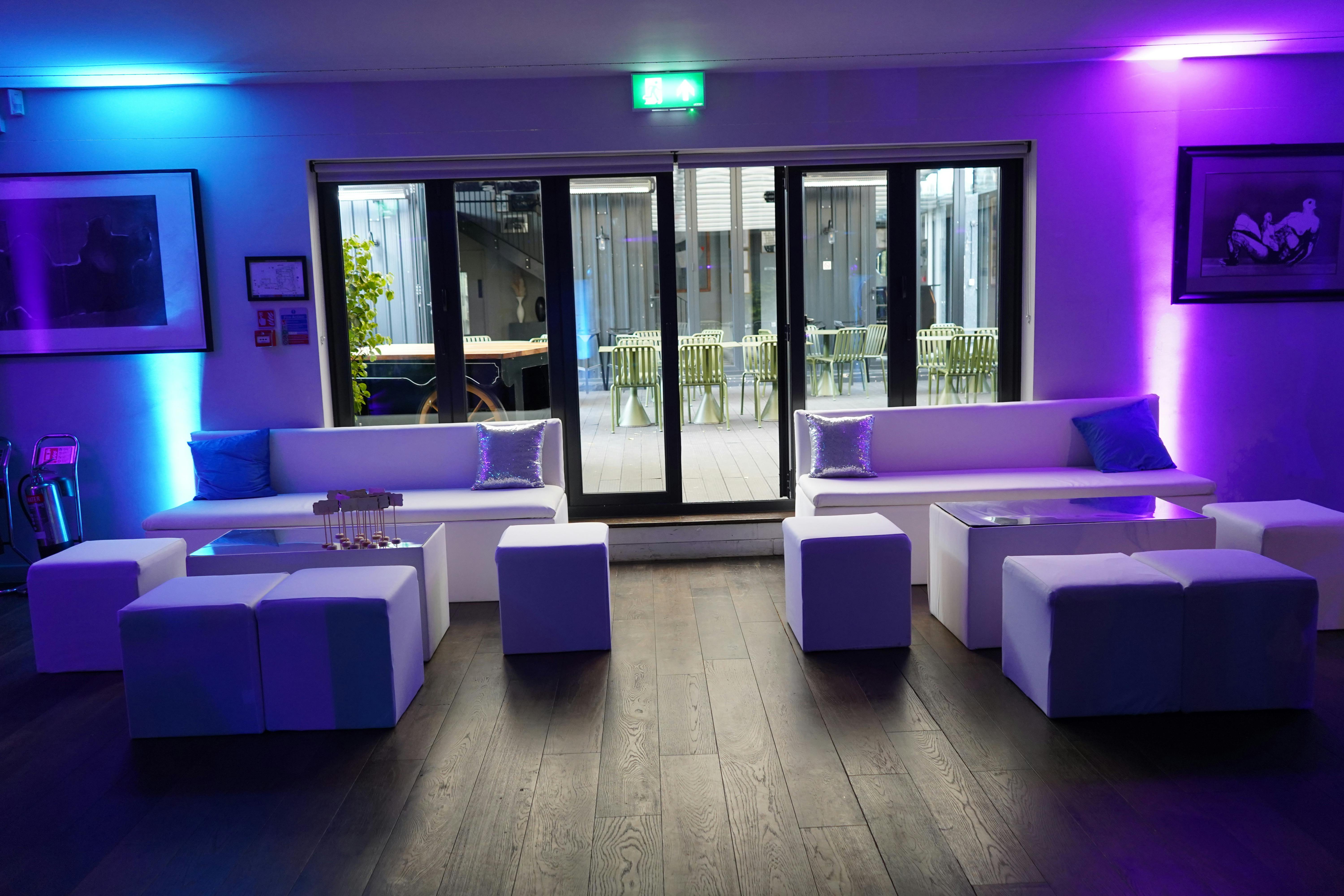 Modern lounge in The V8 Room, featuring sleek white furniture for events and networking.