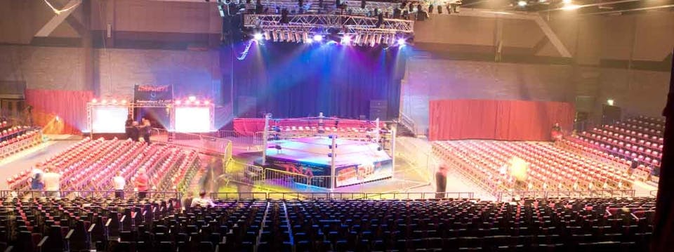 Wrestling match setup in The International Hall, Brentwood Centre with vibrant lighting.