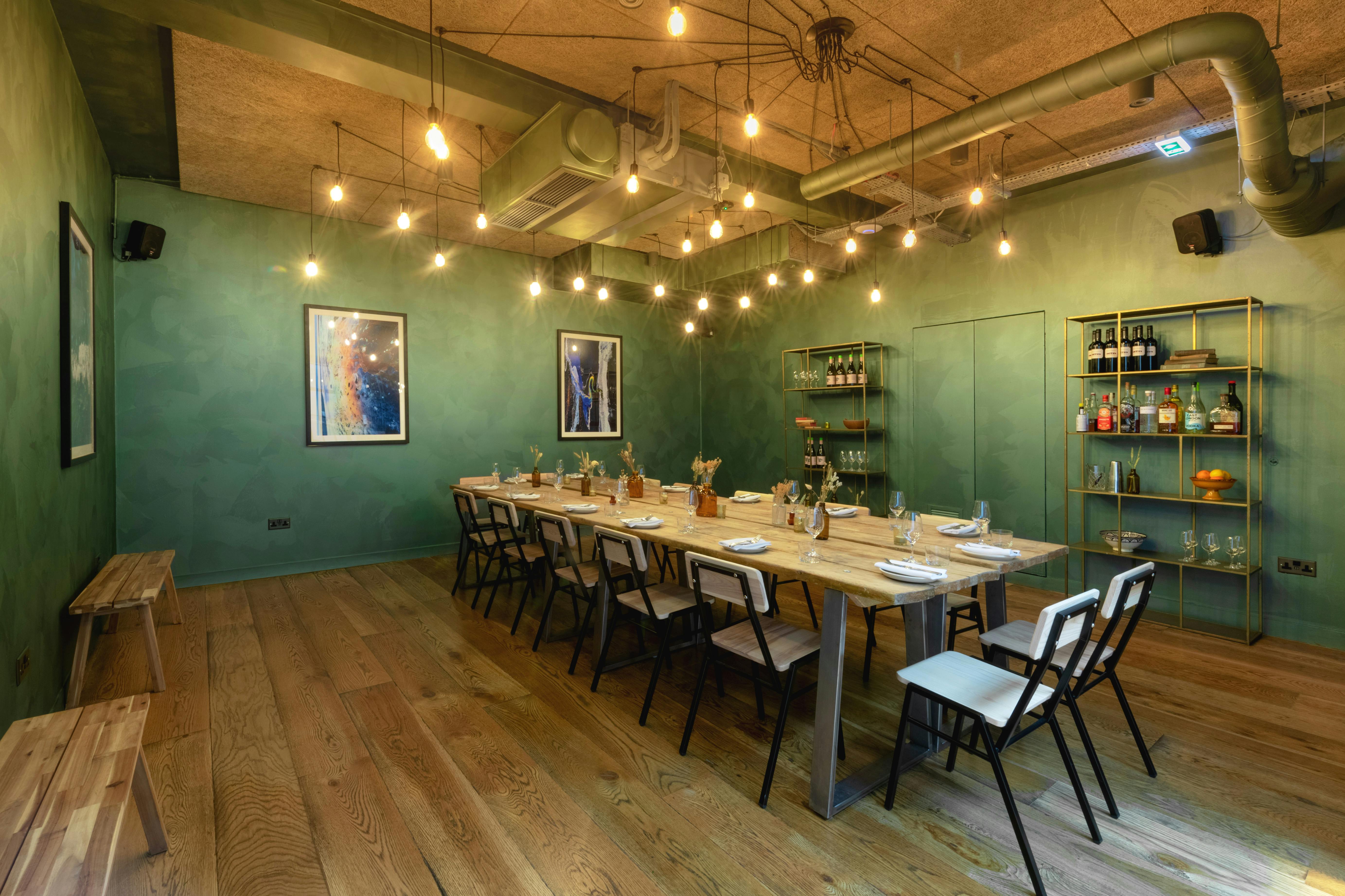 Stylish Green Room in Carousel London, featuring a long wooden table for meetings.