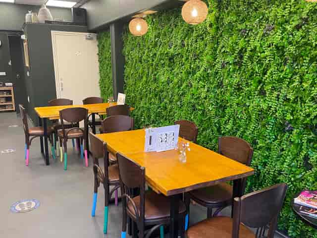 Cozy meeting space at Serenity Cafe with a green living wall for workshops and gatherings.