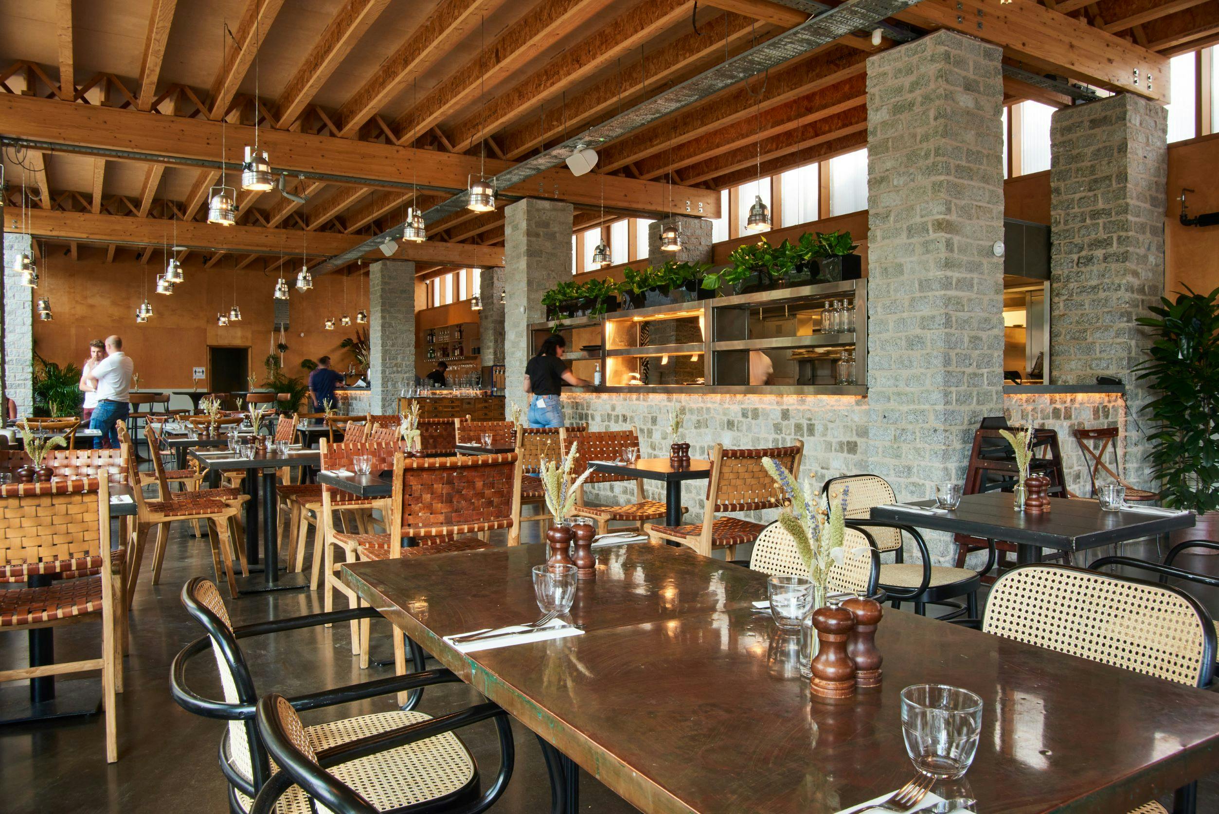 Spacious modern restaurant interior with greenery, perfect for casual dining and events.