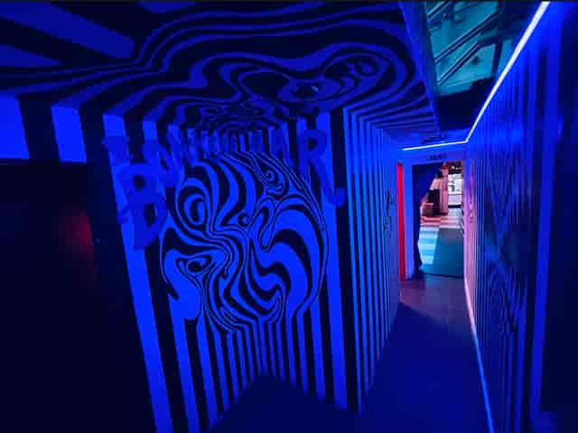 "Bonkers Bar corridor with bold stripes and blue lighting for themed events"