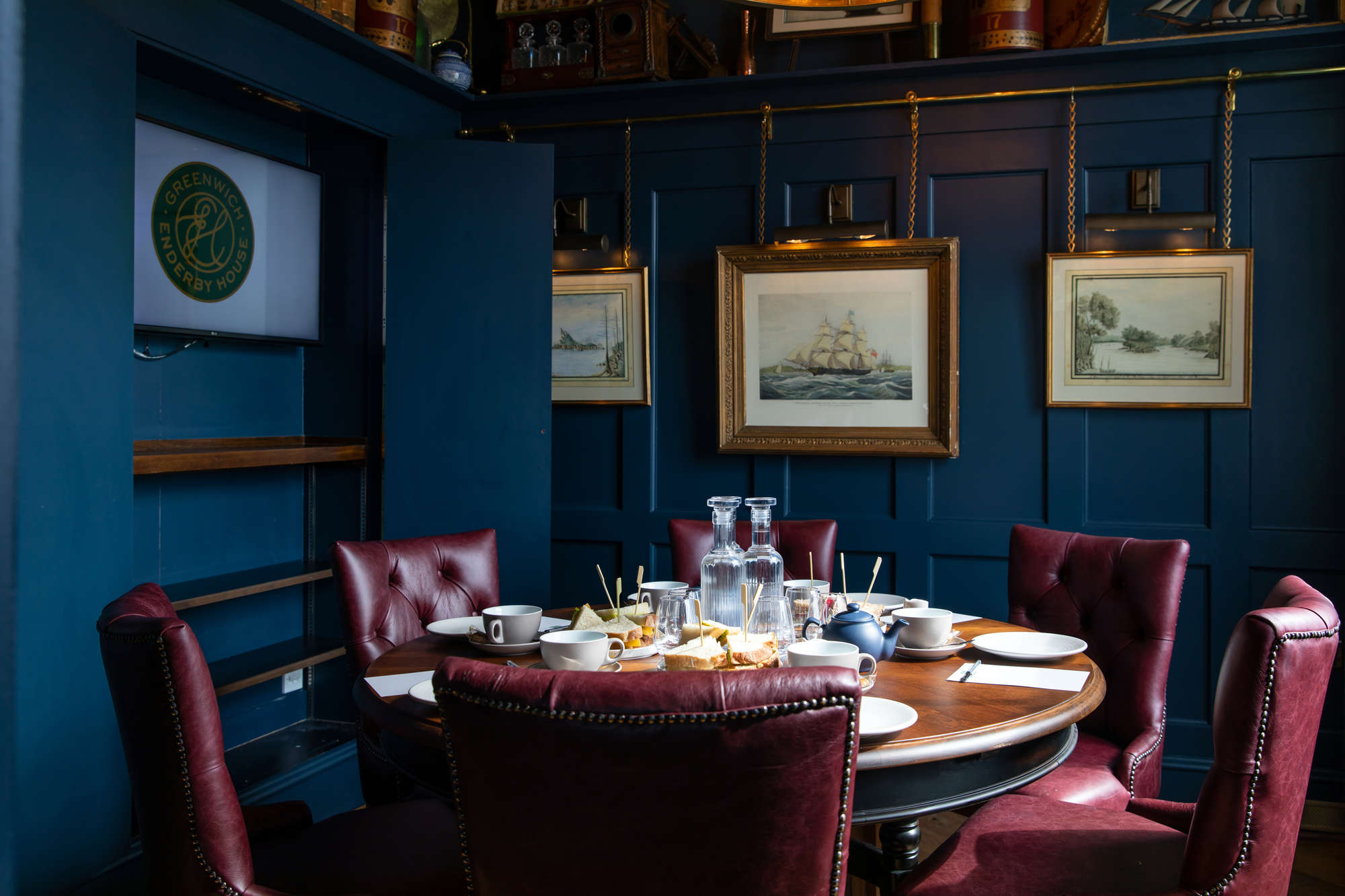 Sophisticated meeting space with round table and burgundy chairs in Enderby House.