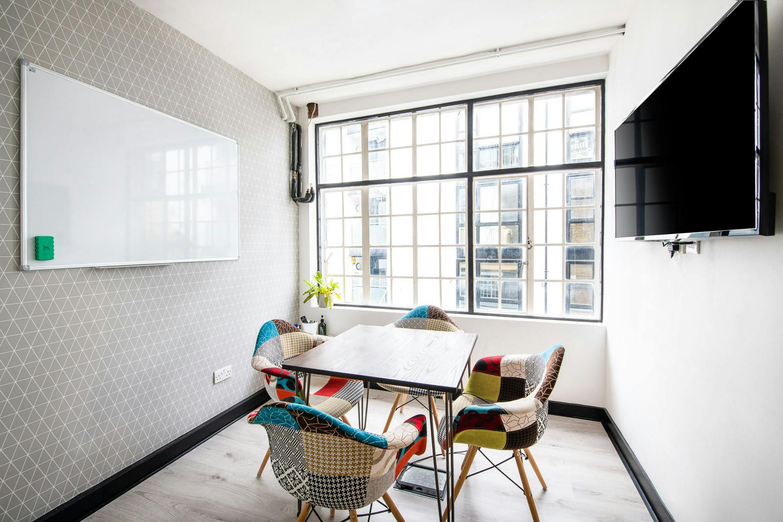 Modern meeting space in Runway East Soho with colorful chairs and natural light.