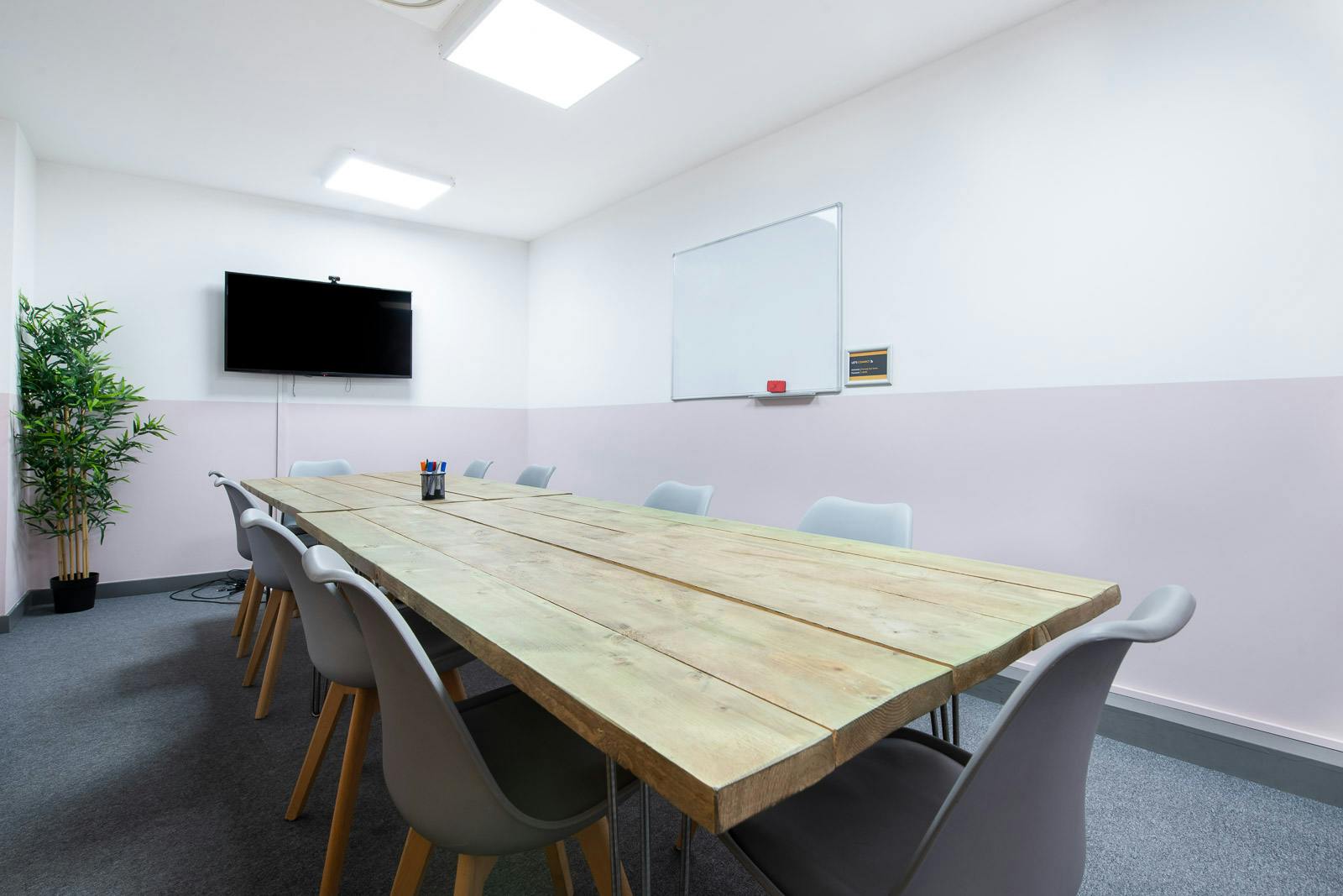 Modern meeting room in Runway East Soho with long wooden table for collaborative sessions.