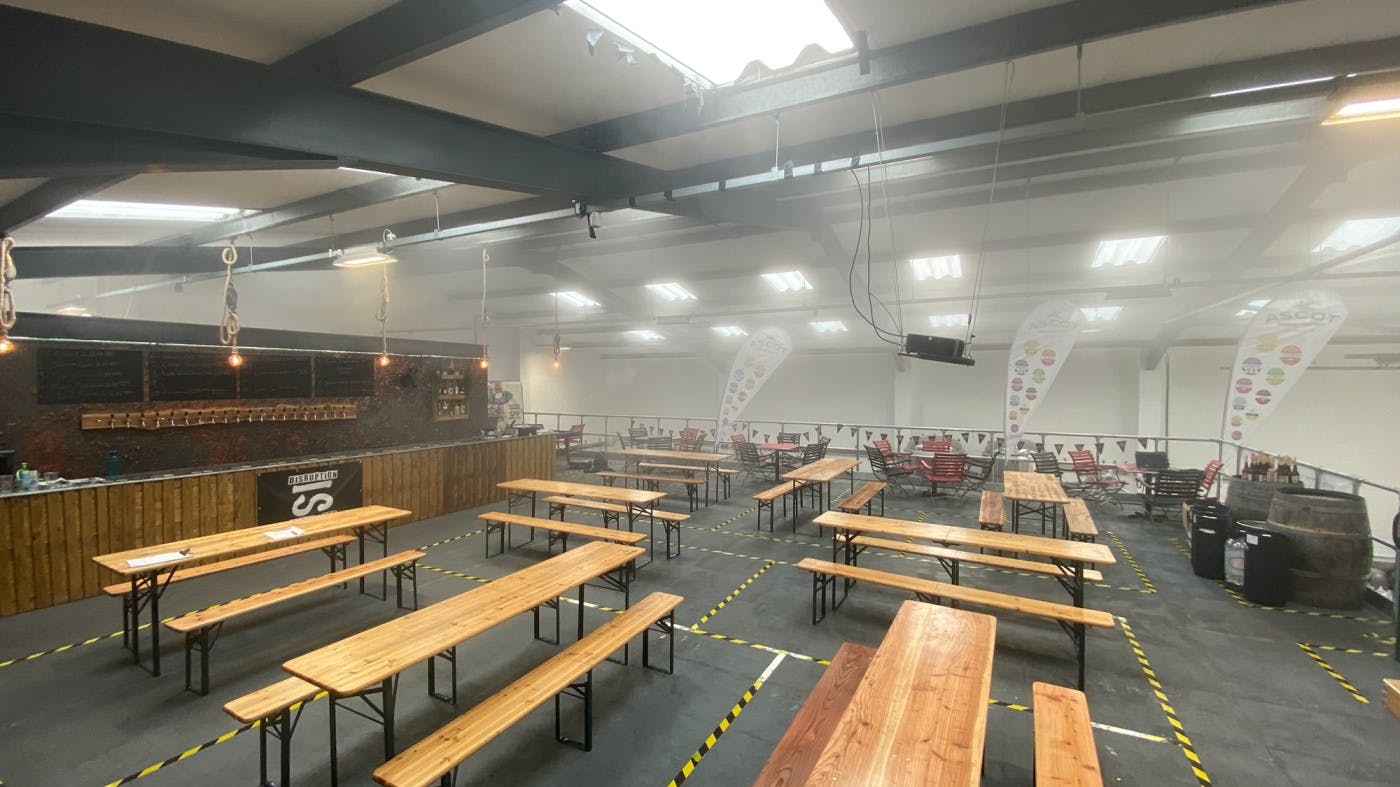 Ascot Brewing event venue with long wooden tables for networking and gatherings.