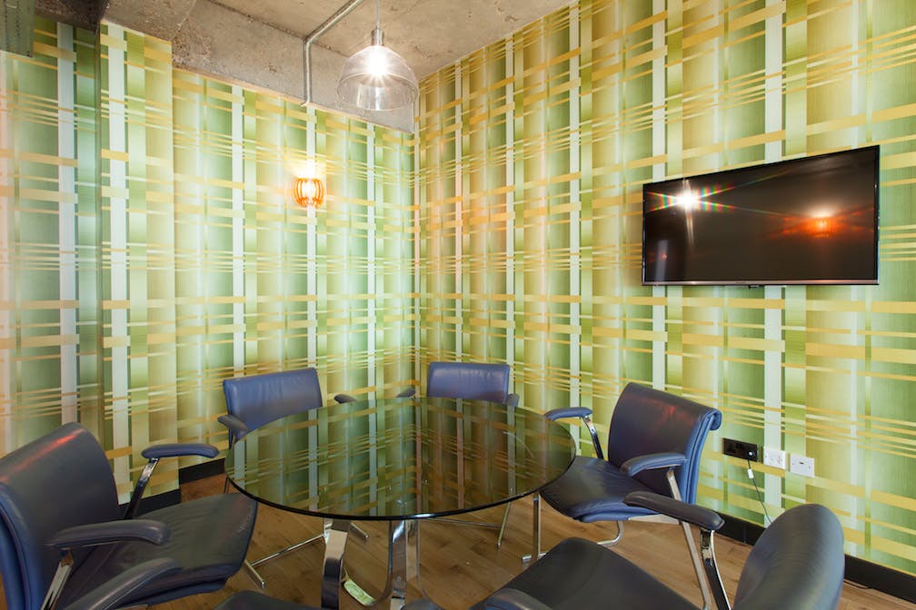 Modern meeting space with round glass table and green wallpaper at The Trampery Old Street.