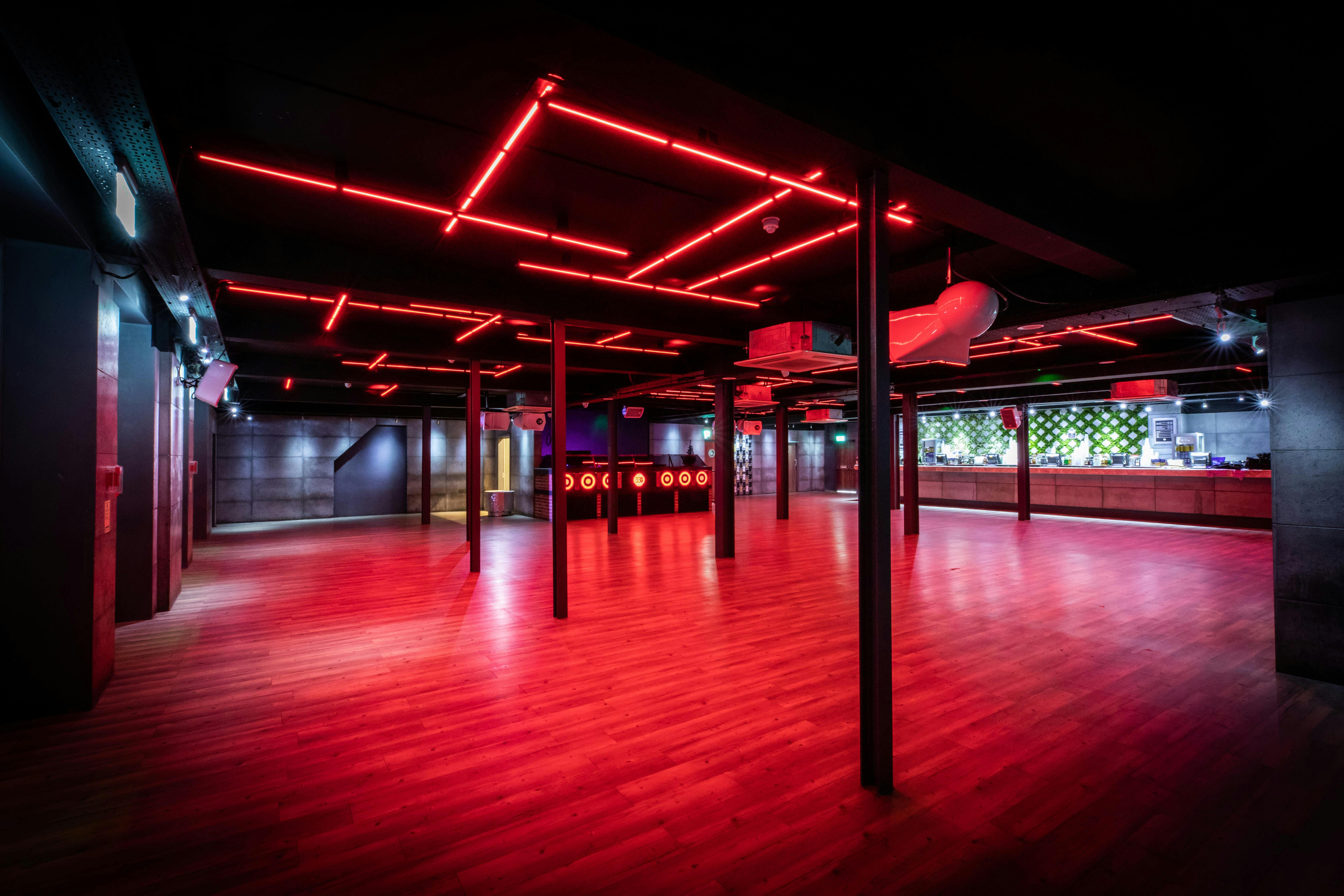 Versatile event space at Studio 338 with red lighting and wooden floor for corporate gatherings.