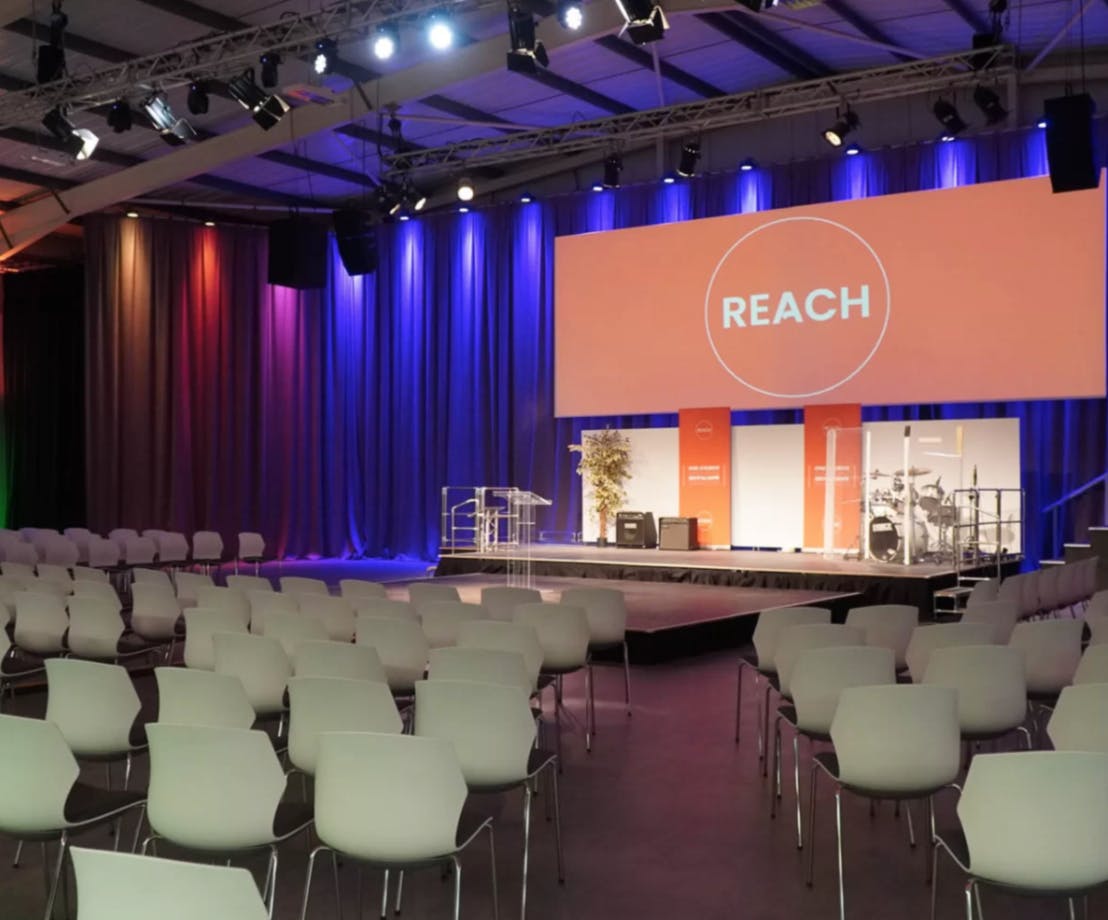 Main Space at Reach Events with stage, modern seating for professional presentations.